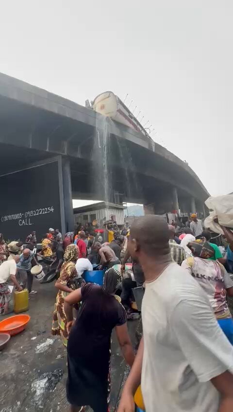 Residents scoop fuel as a diesel tanker falls at Tincan Liverpool Bridge