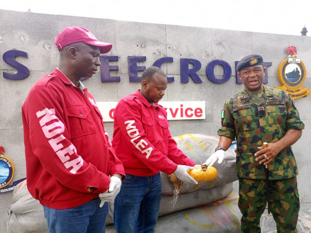 From l- DCN Adejumo Gbenga, NDLEA official and Commander NNS Beecroft, Commodore Aiwiyor Adams-Aliu , displaying a pack of the seized cannabis, during a press briefing at the NNS Beecroft parade ground, Apapa, Lagos.